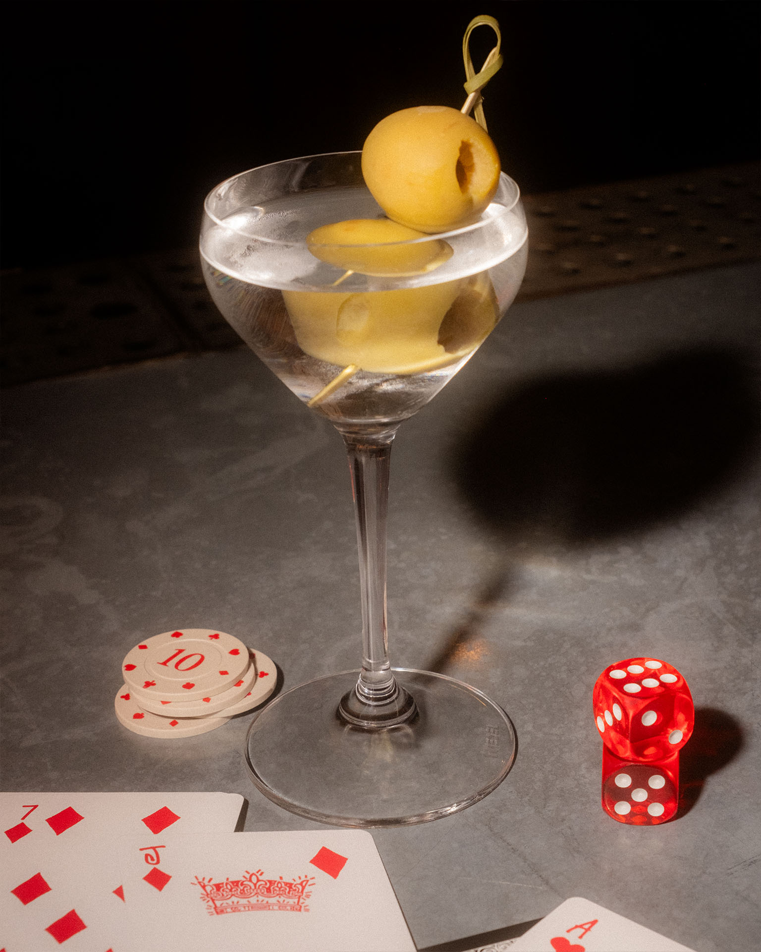 Classic martini with olives on a table with poker chips, playing cards and dice.