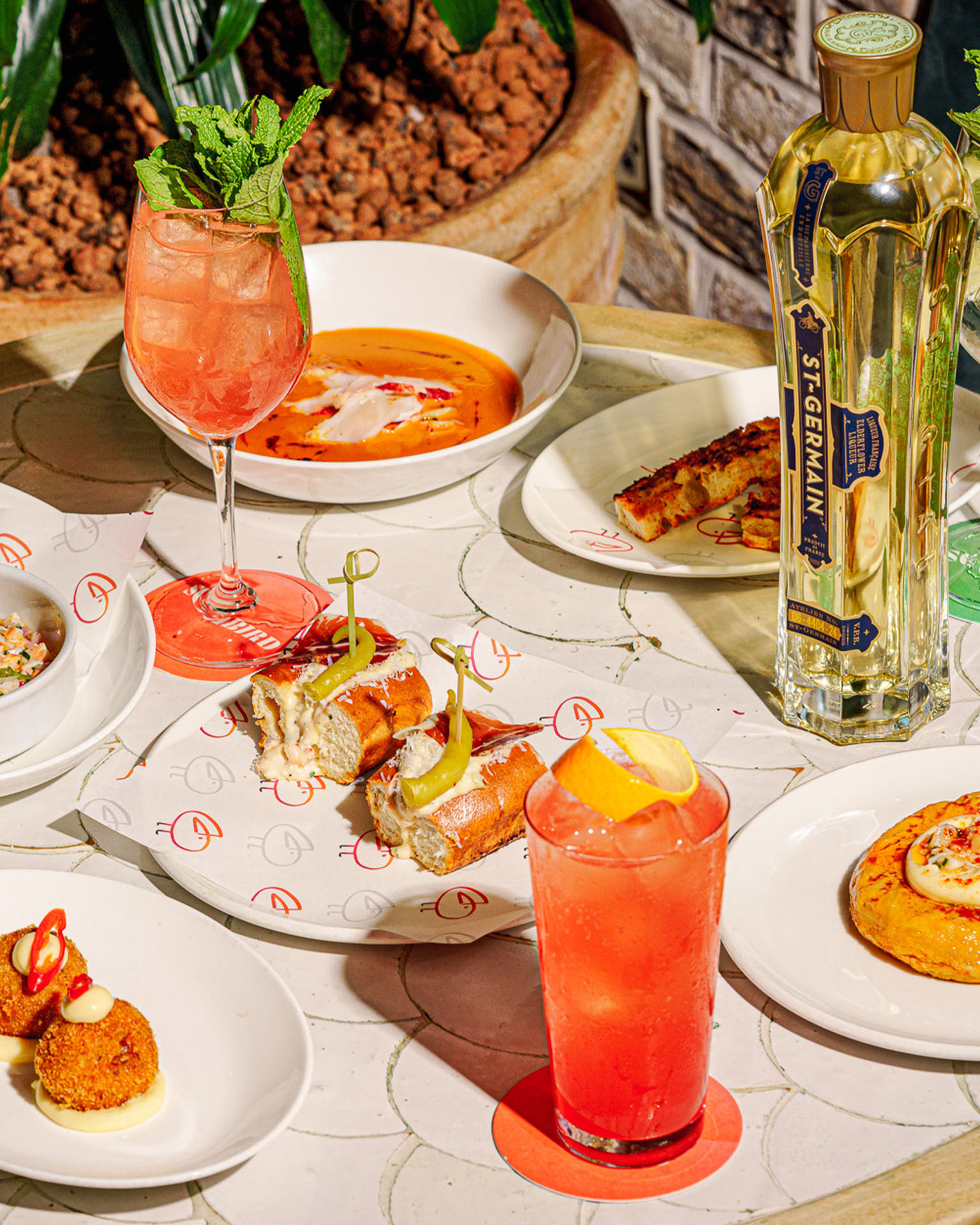 Table with several different lobster dishes paired with colourful orange drinks.